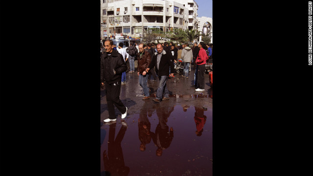 Syrian men walk around a pool of blood at the site of a car bomb explosion in Jaramana on Wednesday. 