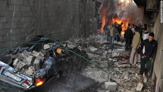 Syrian men inspect the scene of a car bomb explosion on Wednesday in Jaramana, a small town near Damascus that has provided a refuge for pro-government Syrians displaced in the civil war. Twin car bombs near the capital killed dozens, state media reported. 