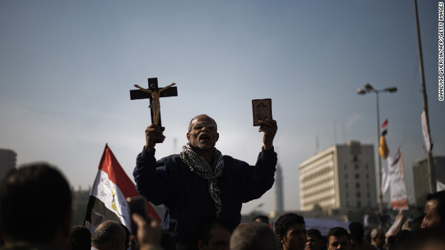 A man holds a copy of the Koran and a cross in Tahrir Square on November 30.