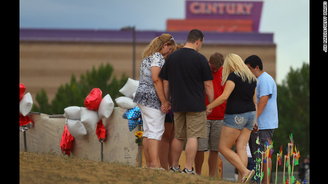 July 28: Visitors gather and pray around a cross erected at a memorial set up across the street from the Century 16 movie theater in Aurora, Colorado. James Holmes is suspected of killing 12 people and injuring 58 others during a shooting rampage on July 20 at a screening of "The Dark Knight Rises."