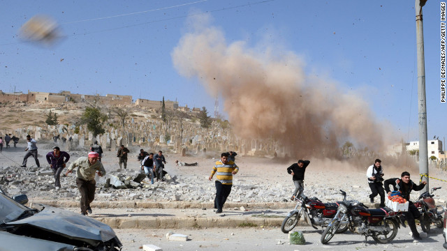 November 4: Syrians take cover as a second bomb explodes during a rescue attempt in a nearby building that was hit during an air raid by government forces in the northern city of Al-Bab.