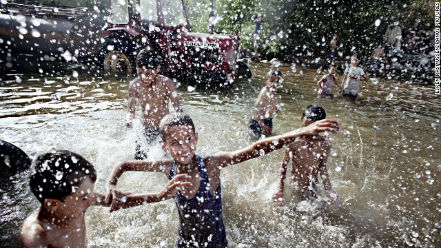 June 15: Lebanese children and Syrian refugees play in a natural spring close to the Syrian border. Behind them, a line of trucks and tractors collect fresh water to supply villages in the area. Tens of thousands of people have fled from Syria to Lebanon since the conflict started.