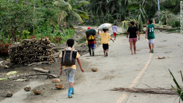 Residents walk down a road covered in debris after the storm in New Bataan on December 5.