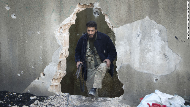 A Syrian rebel fighter emerges from a hole in a wall in Aleppo on December 8.
