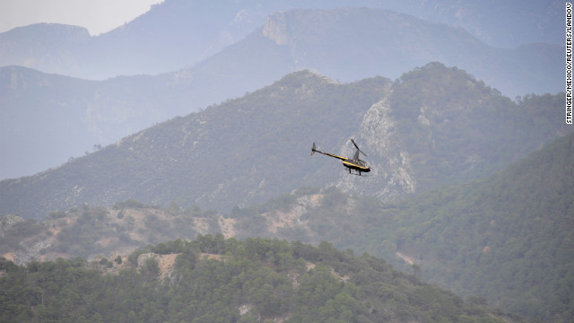 A helicopter flies over the crash site Sunday as investigators search the area. The cause of the crash was not immediately clear.