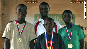 Robert Katende (center, rear) and Phiona Mutesi (right) after the 2009 International Children\'s Chess Tournament in Sudan.\n