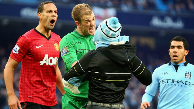 Manchester City goalkeeper Joe Hart confronts a pitch invader trying to harass Manchester United's Ferdinand, who had been hit in the face by a coin thrown from the crowd. 