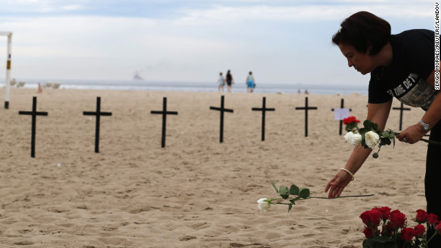 A woman puts a flower near crosses planted by Rio de Paz (Rio of Peace), in memory of the victims of the Sandy Hook Elementary school shooting on Copacabana beach in Rio de Janeiro on December 15.