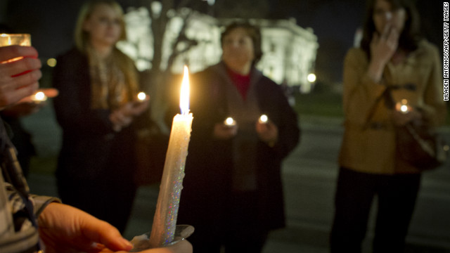 Candles burn as people gather for a vigil outside the White House.