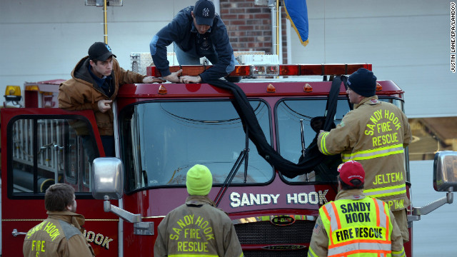 Firefighters attach black bunting to a fire truck as a memorial at the fire station down the street from the Sandy Hook Elementary School in Newtown, Connecticut, on Saturday, December 15. A gunman killed 26 people at the school, including 20 children, before taking his own life on Friday.