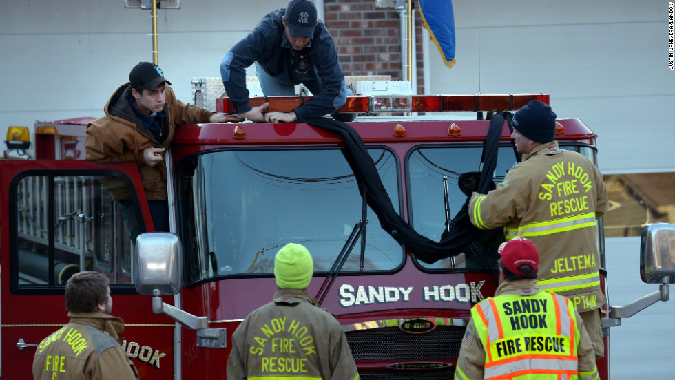 Firefighters attach black bunting to a fire truck as a memorial at the fire station down the street from the Sandy Hook Elementary School in Newtown, Connecticut, on Saturday, December 15. A gunman killed 26 people at the school, including 20 children, before taking his own life on Friday.