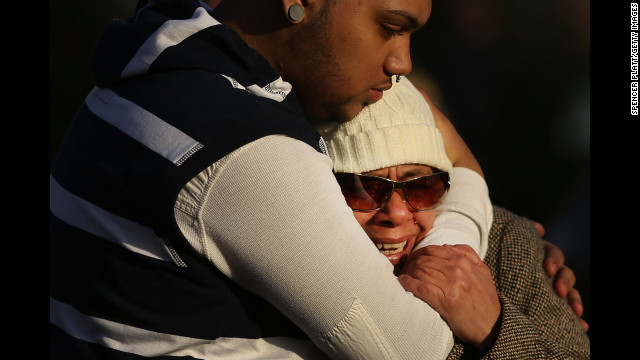 Zulma Sein is hugged by a family member outside of the entrance to the Sandy Hook School on Saturday.