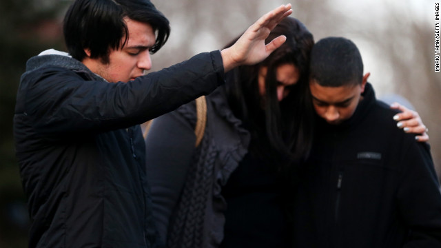 Lucas, Kelly and Michael DaSilva pray and embrace at a makeshift memorial near the school in Newtown.