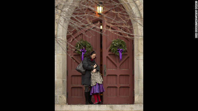 A woman hugs her daughter on the steps of Trinity Church on December 16 in Newtown.