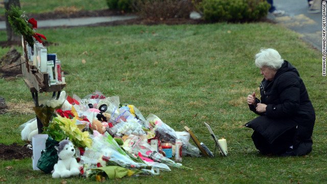 A parishioner kneels in front of a makeshift memorial at St. Rose of Lima Roman Catholic Church in Newtown on December 16.