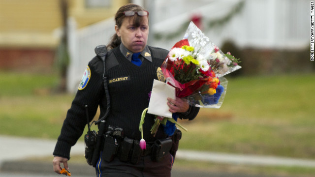 A police officer removes flowers from a busy intersection on December 16 in Newtown. Police said they were afraid the memorial, left for the victims of the Sandy Hook Elementary School shooting, would cause a traffic hazard. 
