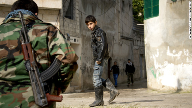 A Syrian boy walks past a rebel fighter in the northern town of Darkush, Syria, on Friday, December 14.