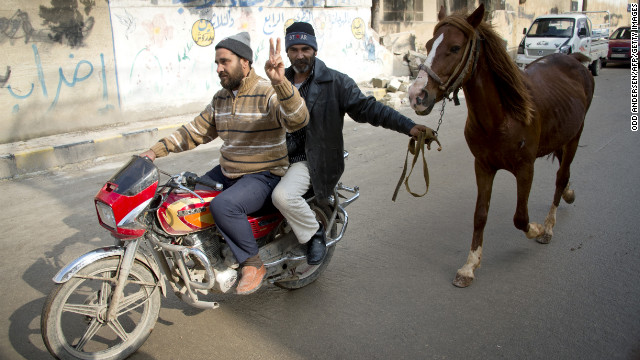 Two men on a motorcycle lead a horse through the northern town of Darkush, Syria, on December 14, 2012.