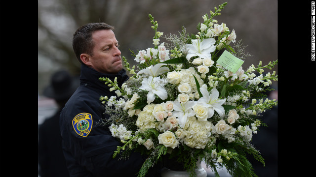 A Fairfield police officer helps move floral arrangements following Noah Pozner's service on December 17 in Fairfield.