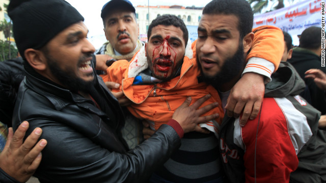 Egyptian men help a wounded comrade during clashes in Alexandria on Friday.