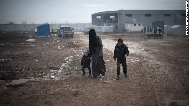 A Syrian mother and her two children walk through the mud after the first snow of the year fell the previous night at a refugee camp in Bab al-Salam on the Syria-Turkey border, on Wednesday, January 9. 