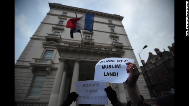 Protesters wave signs outside the French Embassy on Saturday in London.