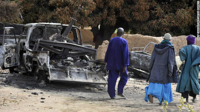 Malians walk past a destroyed truck mounted with a machine gun on Tuesday, January 22. The truck was used by militants and destroyed during airstrikes by the French air force.