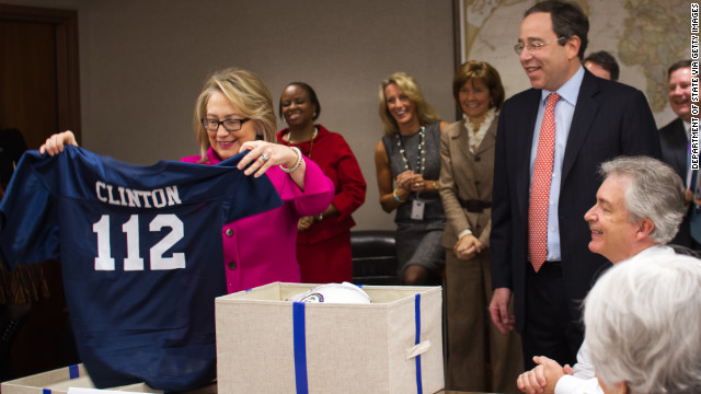  Clinton receives a sports jersey and football helmet from Deputy Secretary Tom Nides, center, after returning to work on January 7, following a fall where she hit her head and doctors later detected a blood clot. The jersey had her last name on the top and with the number 112, which represents the number of countries that she has visited as Secretary of State. 