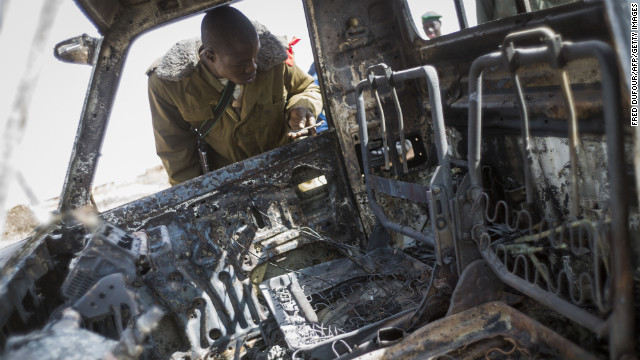 A Malian soldier looks at the wreckage of an Islamist rebel's armed pickup truck in Konna.
