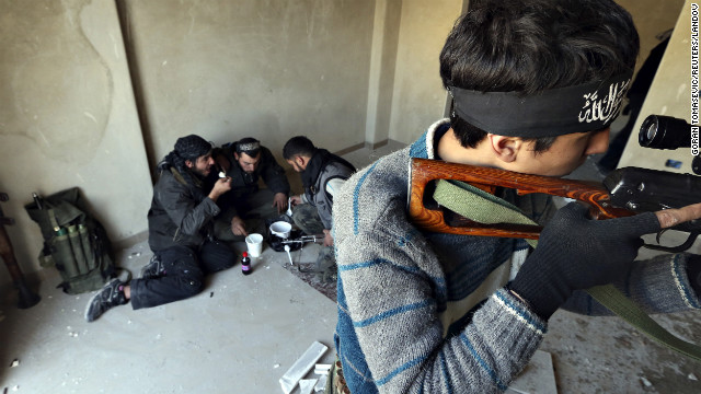 A rebel fighter aims a sniper rifle as other fighters eat their lunch during heavy fighting in Damascus on January 26.