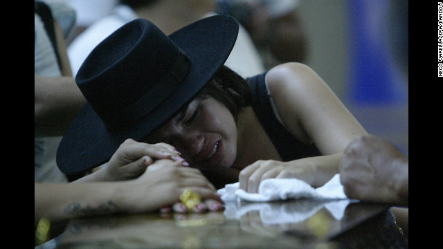 A woman weeps on a coffin as relatives of the nightclub fire victims identify bodies.