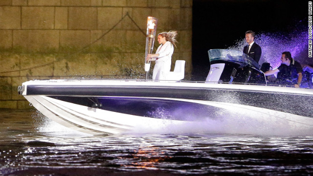 Beckham passes under Tower Bridge in a speedboat which carries the Olympic Torch and its torchbearer in 2012.