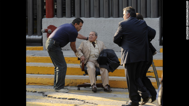 A man at the scene of the blast is helped using a rolling chair near the scene of the explosion.