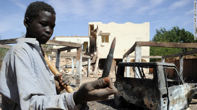A child holds up a machine gun round found in the ruins of a building destroyed by French airstrikes in Douentza, Mali, on February 5.