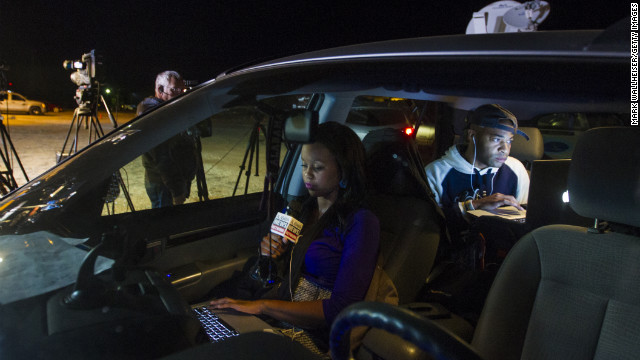 Reporter Ashley Thompson, left, and Marcus Effinger work on a report for Alabama News Network from their vehicle at the site of the standoff on February 4.