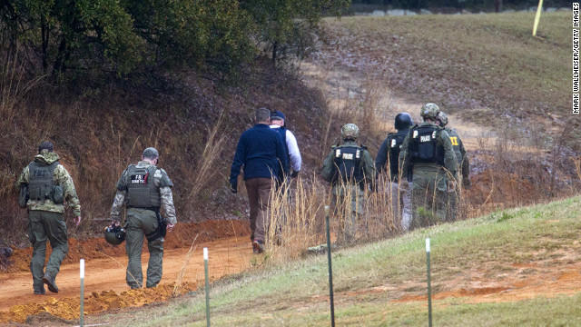 Law enforcement officers walk down a dirt road to the bunker to process the crime scene on Tuesday, February 5, after the standoff ended.