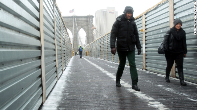 Two people carefully walk across the Brooklyn Bridge in the snow and sleet on February 8.