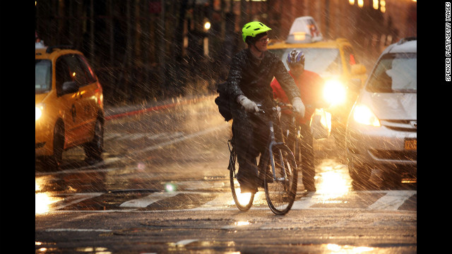 Bicyclists wait at a light in wind, snow and sleet on Friday.