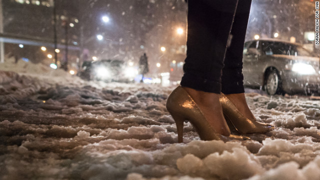 A fashion week attendee makes her way through the snow in high-heeled shoes on Friday.