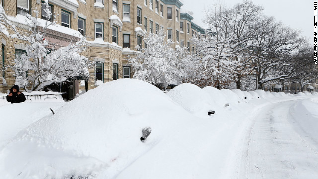 Snow-covered vehicles sit on Commonwealth Avenue in the Brighton neighborhood of Boston on Saturday.