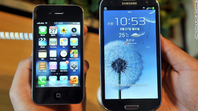 An employee of a mobile phone shop in Seoul, South Korea, holds up the Apple iPhone and a competitor, the Samsung Galaxy.