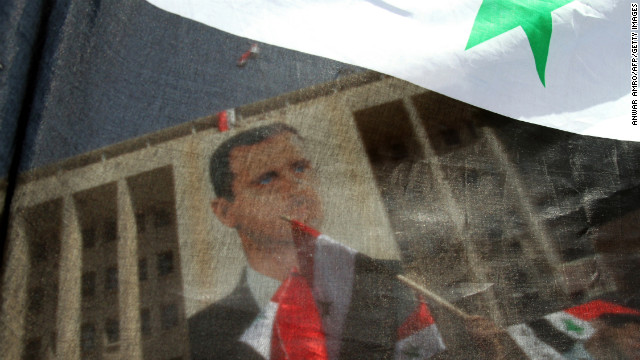 Syrians wave their national flag and hold portraits of al-Assad during a rally to show their support for their leader in Damascus on March 29, 2011.