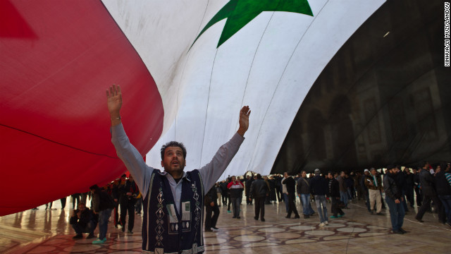 A man stands under a giant Syrian flag outside the Umayyad Mosque in Damascus on December 24, 2011.