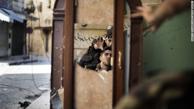 Free Syria Army fighters are reflected in a mirror they use to see a Syrian Army post only 50 meters away in Aleppo on September 16, 2012.