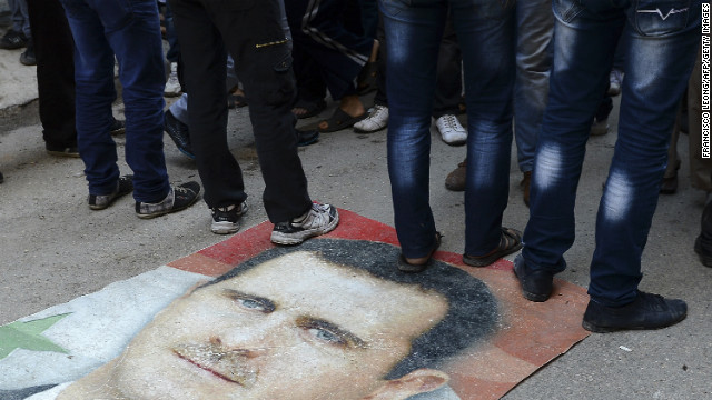 Syrians protesters stand on Assad's portrait during an anti-regime demonstration in Aleppo on November 16, 2012.