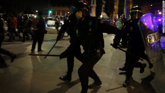 Spanish police in riot gear chase protesters.