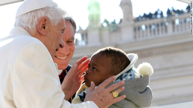 The pope kisses a child as he arrives.