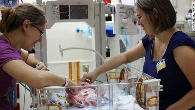 Kelley found a family to adopt the baby while pregnant in Michigan. The family is raising other children who have special needs. Here, Kelley and the baby's adoptive mother admire her in the hospital.