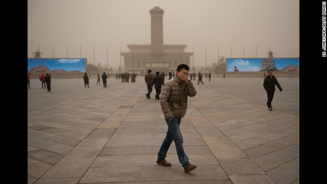 A man covers his face as he walks around Tiananmen Square during a sand storm in heavily polluted weather in Beijing on February 28.