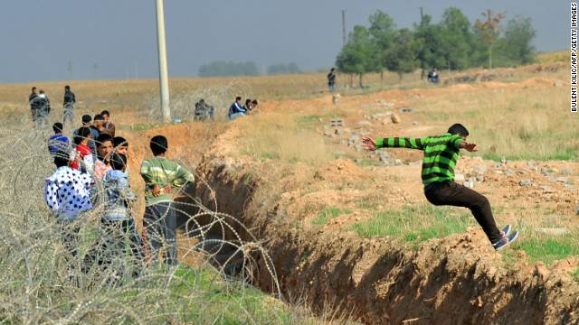 A Syrian jumps across the border between the Syrian town of Ras al-Ain and Ceylanpinar in Turkey's Sanliurfa province on November 10, 2012.